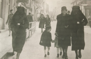 Photo of women and children in street together: A Muslim veiled woman, Zejneba Hardaga (right) and Jewish woman, Rivka Kalb (2nd from right) and her children are guided on the streets of Sarajevo in 1941. Zejneba covered the yellow star on the Rivka's left arm with her veil. Bahrija Hardasa, sister-in-law of Zejneba, is on the far left.
